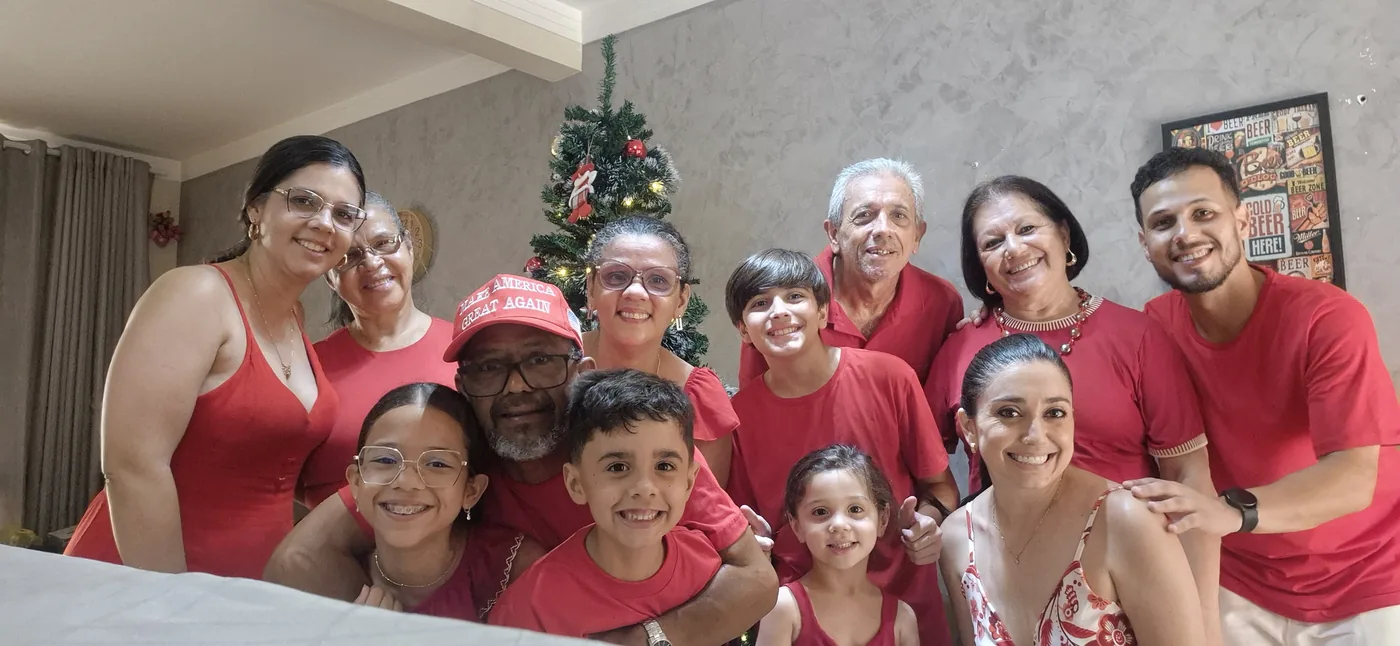 Família toda reunida de vermelho em frente à árvore de Natal